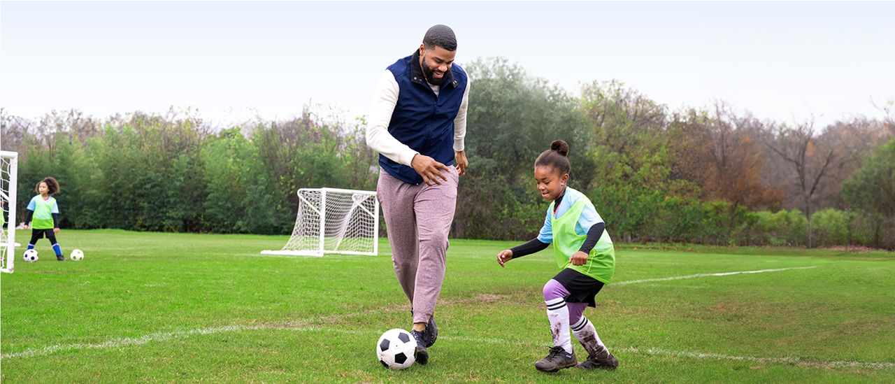 Man playing soccer with daughter